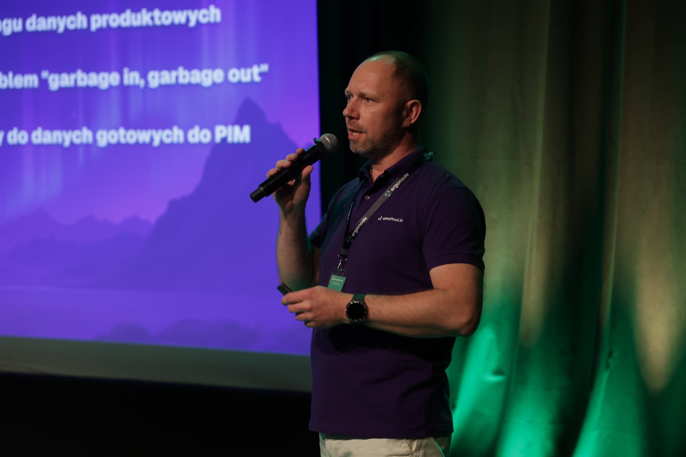 Olgierd Mrozik giving the openProd talk on stage at GRID#26, with a slide behind him